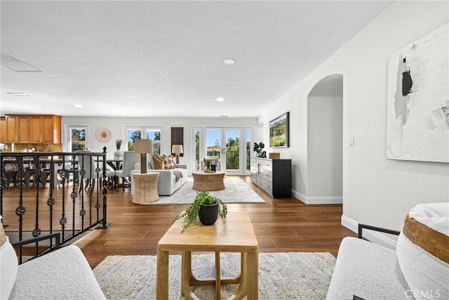 living area featuring arched walkways, recessed lighting, baseboards, and wood finished floors