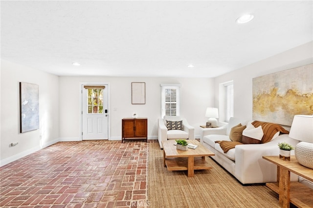 living area featuring recessed lighting, brick floor, and baseboards