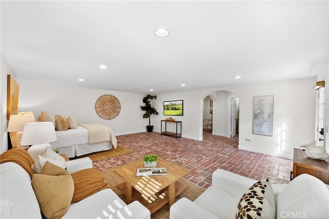 living area with brick floor, baseboards, arched walkways, and recessed lighting