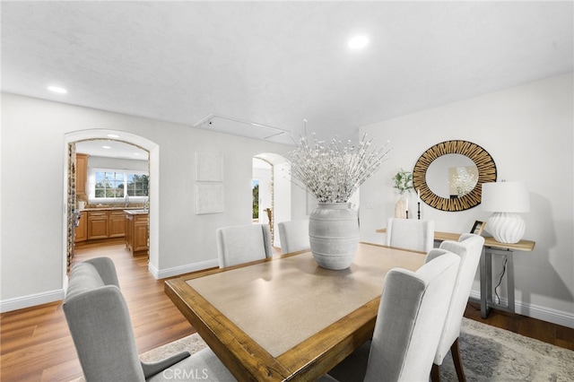 dining area with arched walkways, light wood-type flooring, baseboards, and recessed lighting