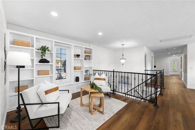 sitting room with plenty of natural light, wood finished floors, an upstairs landing, and recessed lighting