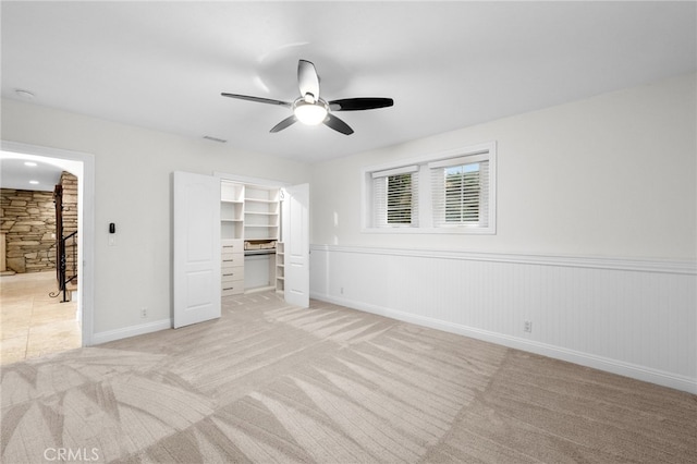 unfurnished bedroom with visible vents, a ceiling fan, light colored carpet, a spacious closet, and a closet