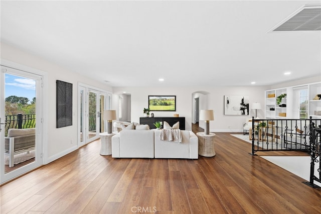 living area featuring arched walkways, baseboards, visible vents, and hardwood / wood-style floors