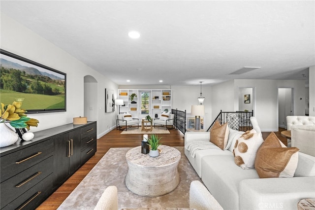 living room with dark wood-type flooring, recessed lighting, arched walkways, and baseboards