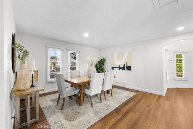 dining area with arched walkways, recessed lighting, baseboards, and wood finished floors