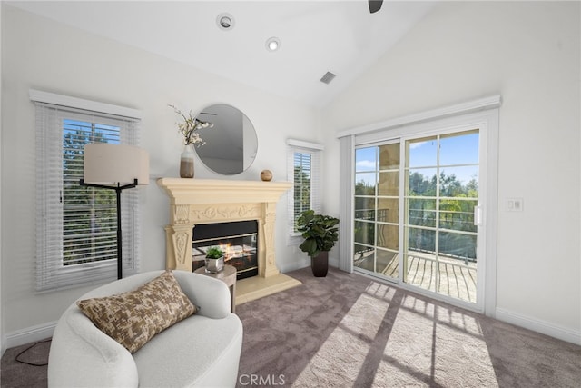 carpeted living room with high vaulted ceiling, a glass covered fireplace, visible vents, and baseboards