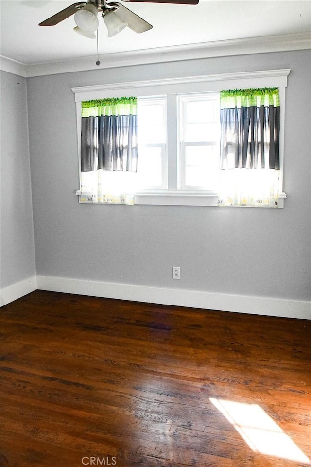 unfurnished room with ornamental molding, baseboards, and wood finished floors