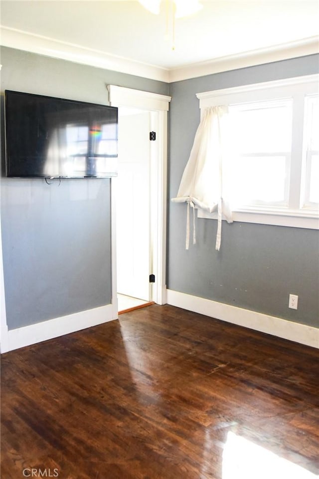 spare room featuring baseboards and wood finished floors