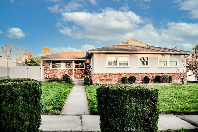 view of front of home featuring brick siding, stucco siding, fence, and a front yard