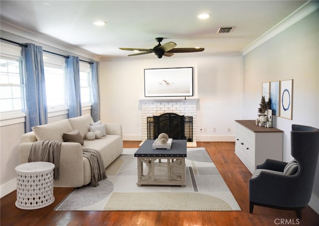 living room featuring crown molding, a fireplace, baseboards, and wood finished floors