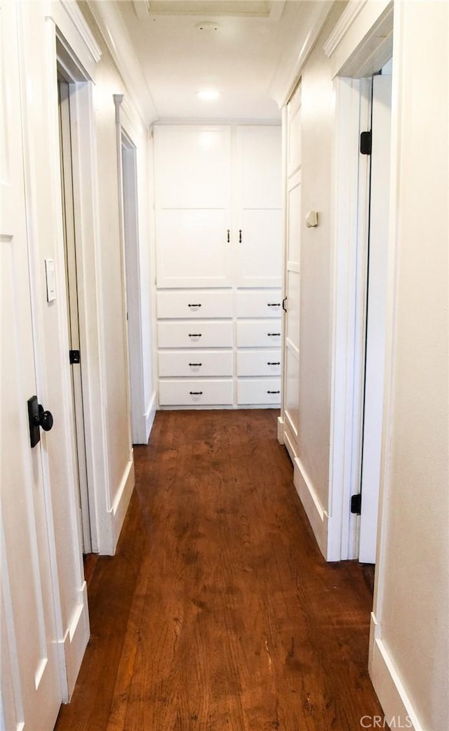 corridor featuring baseboards and dark wood-type flooring