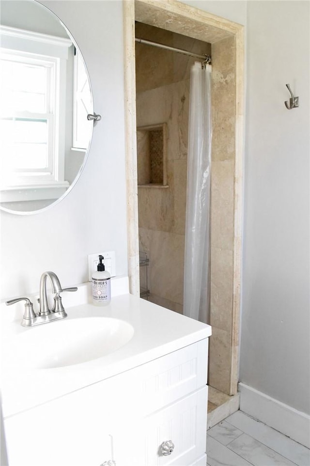 full bathroom featuring marble finish floor, a shower with curtain, baseboards, and vanity