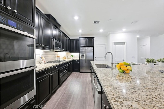 kitchen with sink, light stone counters, crown molding, stainless steel appliances, and decorative backsplash