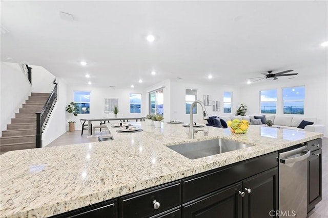 kitchen with light stone counters, dishwasher, sink, and a wealth of natural light