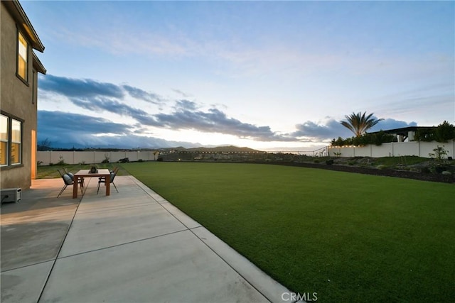 yard at dusk featuring a mountain view and a patio area