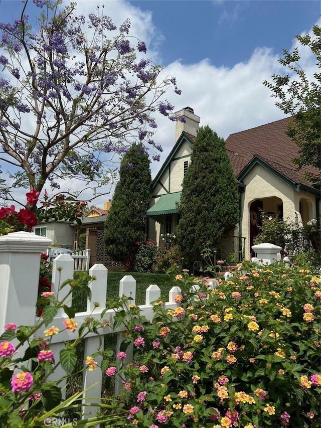 view of front of home featuring a fenced front yard, a chimney, and stucco siding