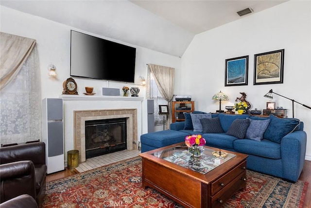 living room with lofted ceiling, visible vents, a fireplace, and wood finished floors