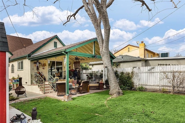 rear view of property with a yard, stucco siding, a patio, and fence