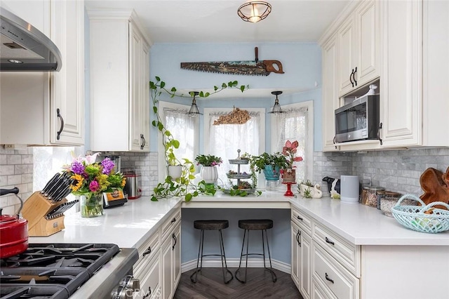 kitchen with light countertops, stainless steel microwave, wall chimney exhaust hood, and white cabinets