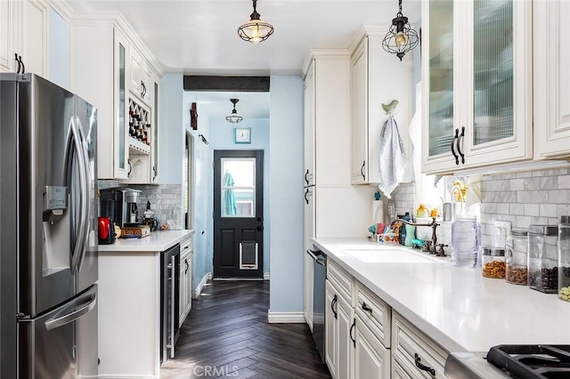 kitchen featuring stainless steel appliances, light countertops, hanging light fixtures, and glass insert cabinets