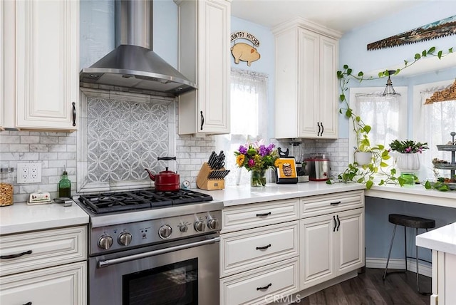 kitchen featuring wall chimney range hood, light countertops, and high end stainless steel range