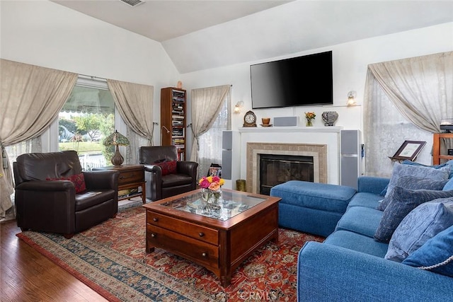 living area featuring dark wood-style floors, lofted ceiling, and a tile fireplace