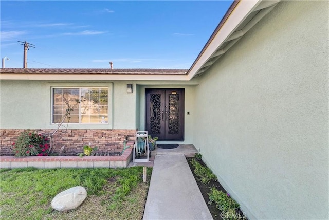 view of exterior entry featuring stone siding and stucco siding