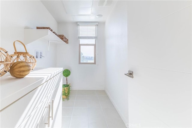 laundry area featuring laundry area, light tile patterned flooring, and baseboards