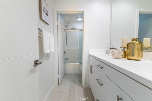 bathroom featuring enclosed tub / shower combo, vanity, toilet, and tile patterned floors