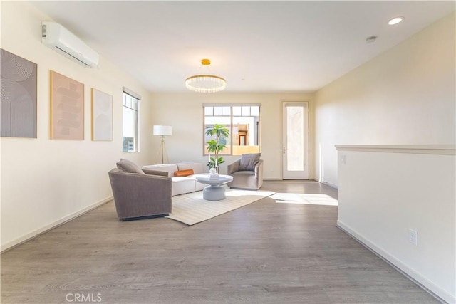 living room featuring recessed lighting, baseboards, an AC wall unit, and wood finished floors