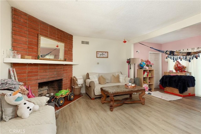 living room featuring hardwood / wood-style flooring, a textured ceiling, and a fireplace