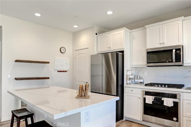 kitchen featuring white cabinets, stainless steel appliances, open shelves, and light wood-style floors