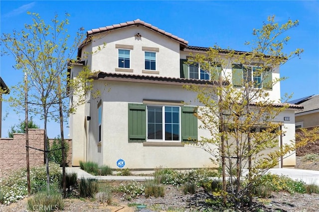 view of front of property featuring fence, a tile roof, and stucco siding