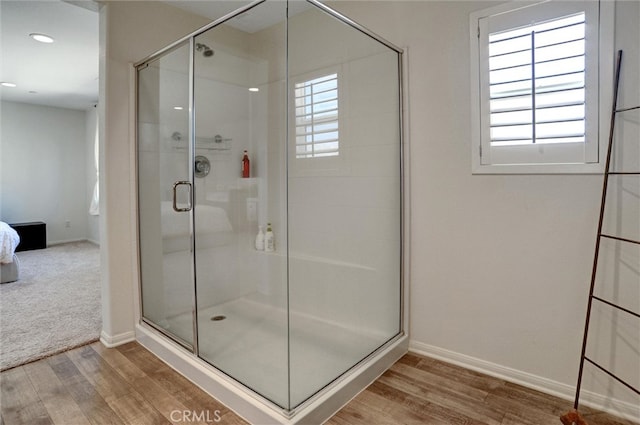bathroom with recessed lighting, baseboards, wood finished floors, and a stall shower