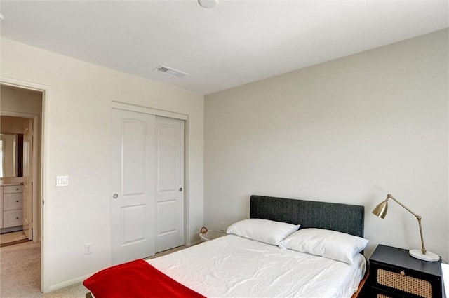 bedroom featuring baseboards, visible vents, light carpet, and a closet