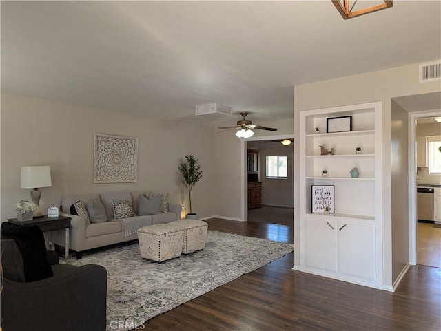 living room with dark hardwood / wood-style flooring, ceiling fan, and built in shelves