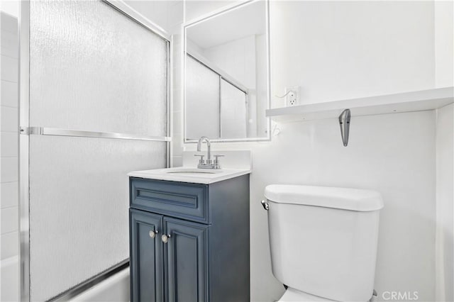 full bathroom featuring vanity, combined bath / shower with glass door, and toilet