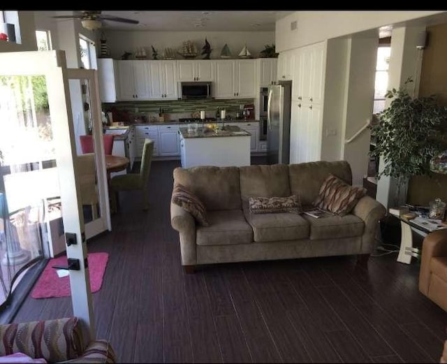 living room featuring dark wood-style floors, ceiling fan, and a wealth of natural light