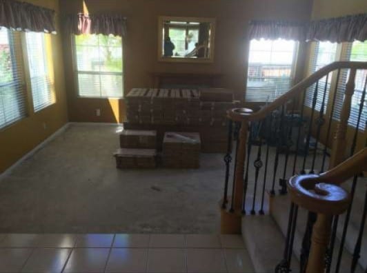 carpeted living room featuring a healthy amount of sunlight, stairs, and tile patterned floors