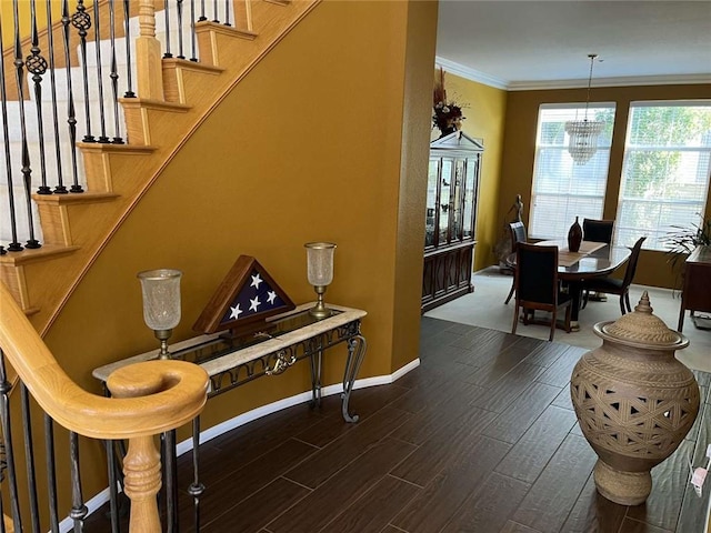 stairway with a chandelier, crown molding, baseboards, and wood finished floors