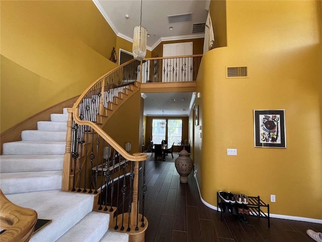 stairs with baseboards, wood finished floors, visible vents, and crown molding