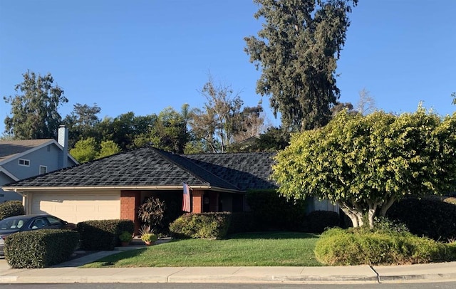 ranch-style home featuring roof with shingles, an attached garage, and a front yard