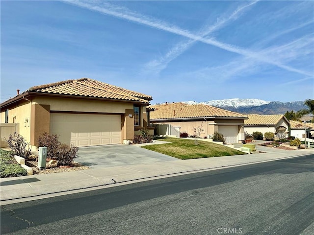 view of front of home featuring stucco siding, concrete driveway, a mountain view, a garage, and a tiled roof