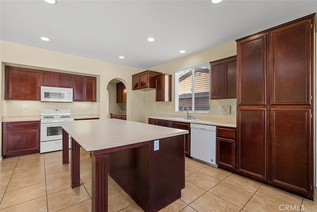 kitchen featuring white appliances, a kitchen island, arched walkways, and light countertops