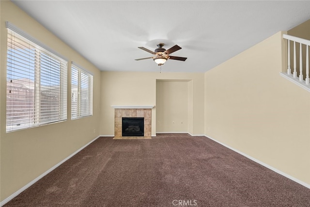 unfurnished living room featuring carpet, a tiled fireplace, a ceiling fan, and baseboards