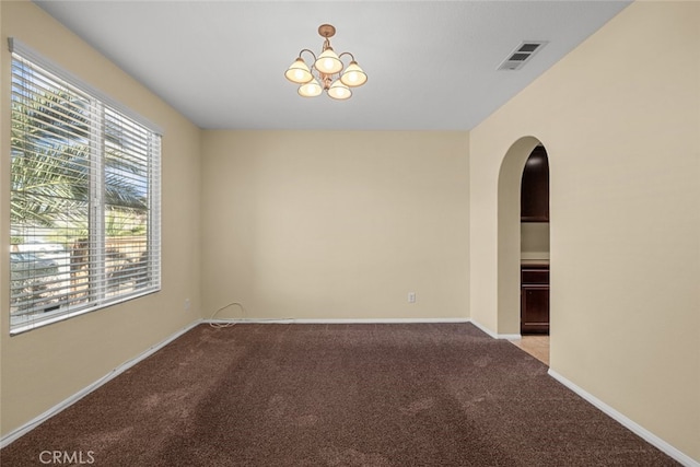 empty room featuring arched walkways, visible vents, an inviting chandelier, light carpet, and baseboards