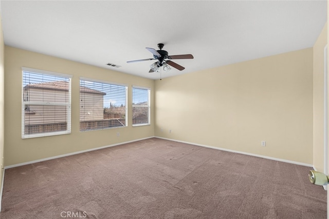 carpeted empty room with a ceiling fan, visible vents, and baseboards