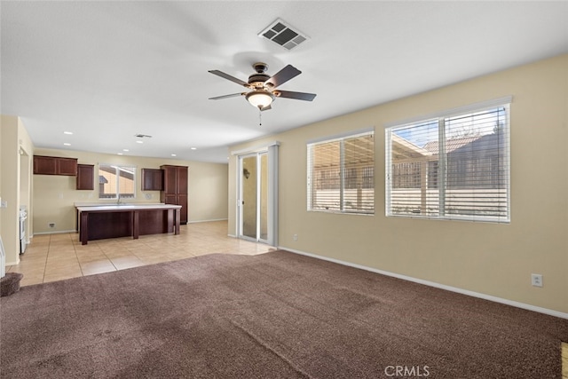 unfurnished living room with visible vents, light carpet, baseboards, and light tile patterned floors