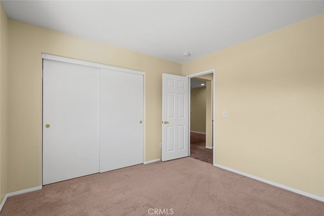 unfurnished bedroom with carpet floors, a closet, and baseboards