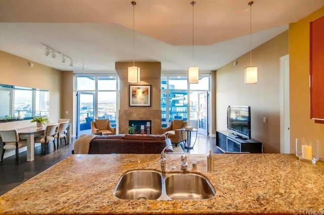 kitchen with sink, decorative light fixtures, light stone countertops, and expansive windows